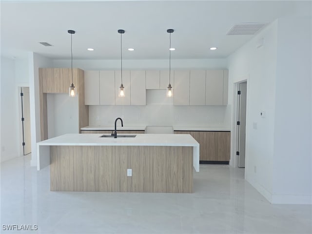 kitchen featuring decorative backsplash, a kitchen island with sink, sink, and pendant lighting