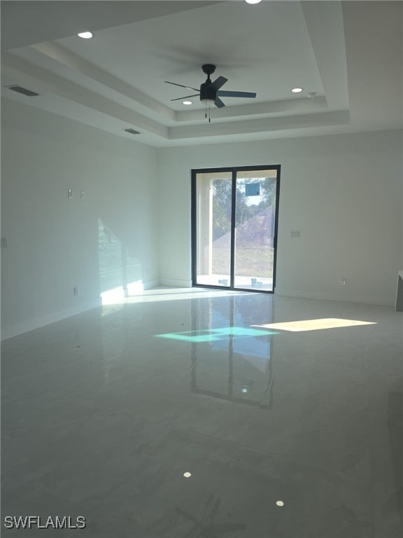 empty room featuring a raised ceiling and ceiling fan