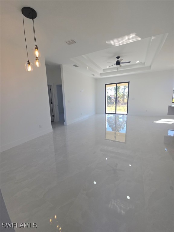 empty room with ceiling fan and a tray ceiling