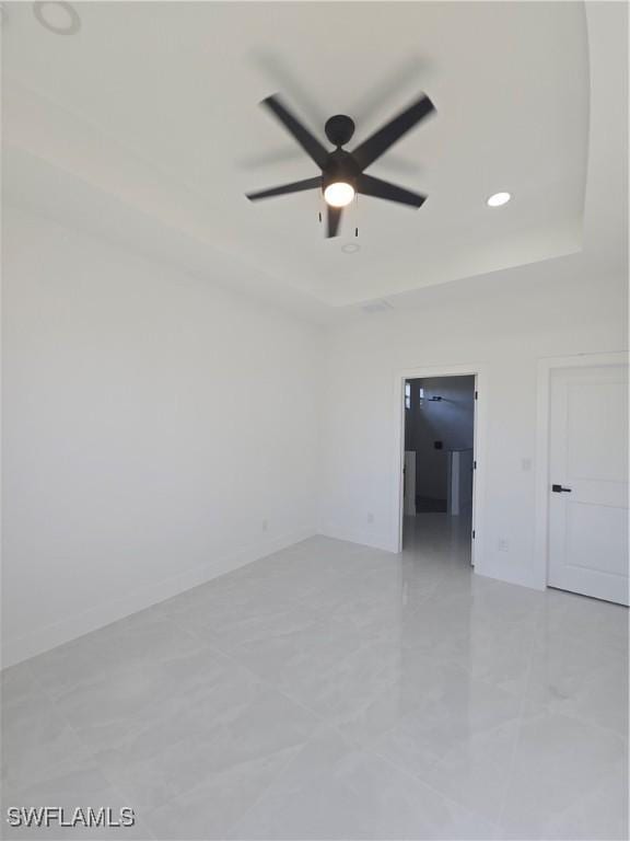 empty room with a raised ceiling and ceiling fan