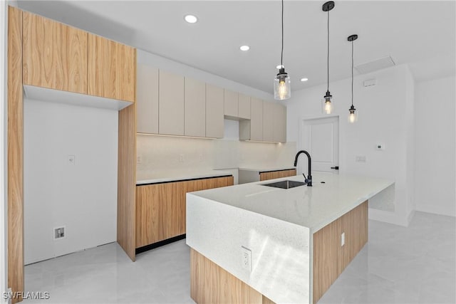 kitchen featuring sink, white cabinetry, decorative light fixtures, a kitchen island with sink, and backsplash