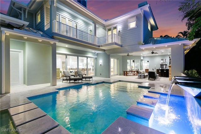 pool at dusk featuring pool water feature, a patio area, and ceiling fan