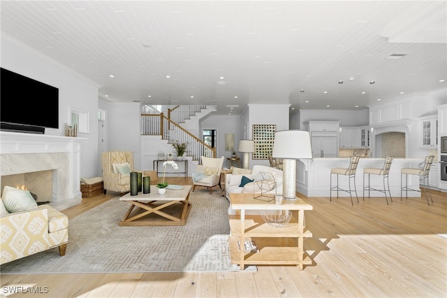 living room with wood ceiling, a premium fireplace, light hardwood / wood-style flooring, and crown molding