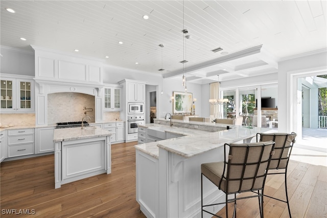 kitchen with a large island, stainless steel appliances, hanging light fixtures, decorative backsplash, and white cabinets