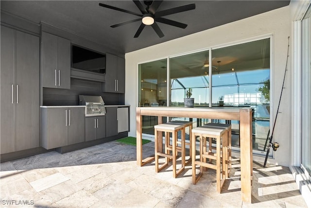 view of patio / terrace featuring grilling area, ceiling fan, exterior bar, and exterior kitchen