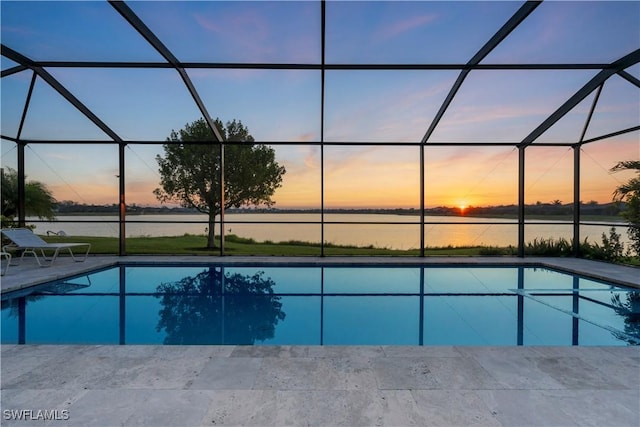 pool at dusk with a patio, a water view, and glass enclosure