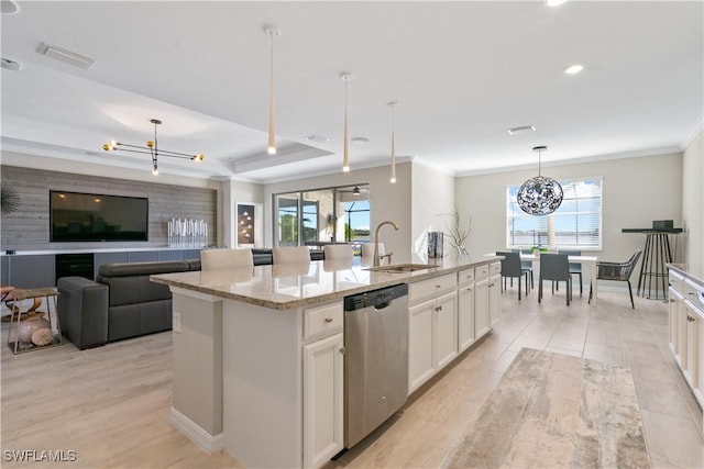 kitchen with pendant lighting, a center island with sink, white cabinets, sink, and stainless steel dishwasher