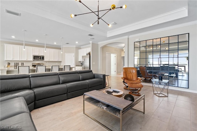 living room with light tile patterned floors, crown molding, a tray ceiling, and an inviting chandelier