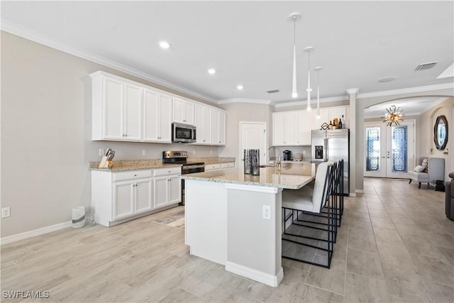 kitchen featuring french doors, hanging light fixtures, an island with sink, white cabinetry, and stainless steel appliances