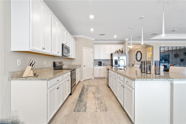 kitchen featuring appliances with stainless steel finishes, decorative light fixtures, white cabinetry, and a large island with sink