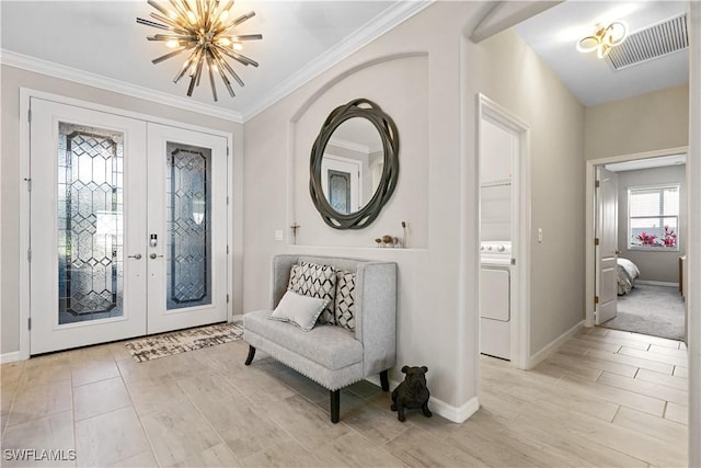 entryway featuring a chandelier, washer / dryer, ornamental molding, and french doors