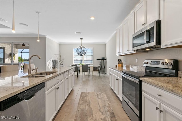 kitchen with appliances with stainless steel finishes, light stone counters, sink, decorative light fixtures, and white cabinets