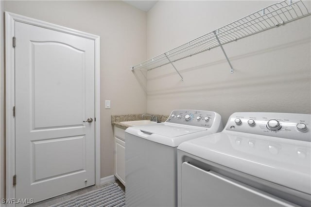 clothes washing area with washer and clothes dryer, cabinets, and sink