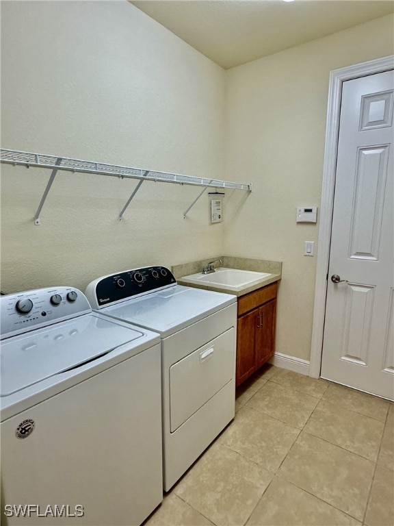 clothes washing area featuring cabinets, separate washer and dryer, sink, and light tile patterned floors