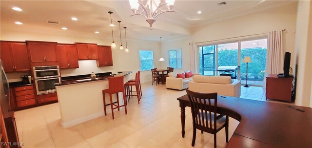 kitchen with stainless steel double oven, a notable chandelier, decorative light fixtures, a kitchen bar, and ornamental molding