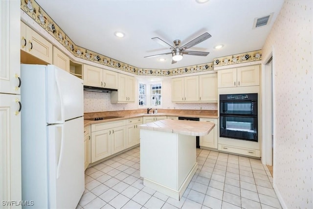 kitchen featuring a center island, black appliances, sink, ceiling fan, and tile counters