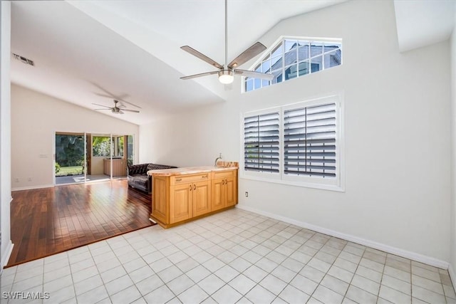 kitchen with ceiling fan, lofted ceiling, and light tile patterned floors