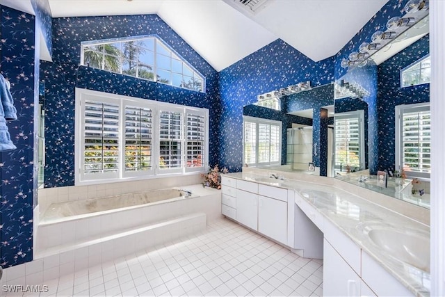 bathroom with vanity, tile patterned floors, lofted ceiling, and tiled tub