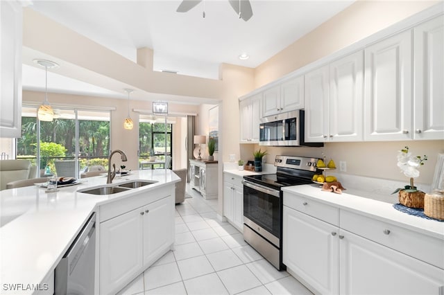 kitchen with pendant lighting, white cabinets, sink, light tile patterned floors, and appliances with stainless steel finishes