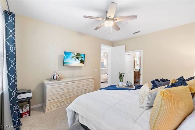 bedroom with ceiling fan, light colored carpet, and ensuite bathroom