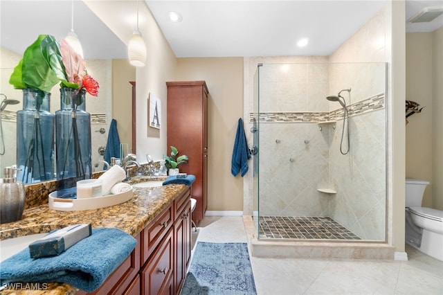 bathroom featuring tile patterned flooring, a tile shower, vanity, and toilet