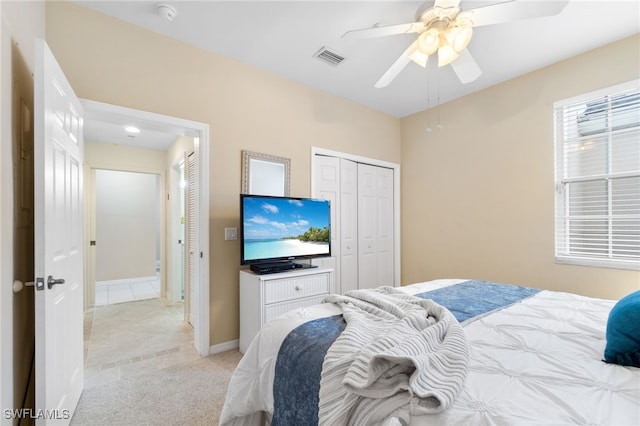 bedroom featuring ceiling fan, light carpet, and a closet