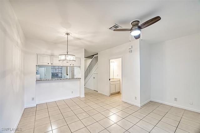 spare room with light tile patterned floors and ceiling fan with notable chandelier