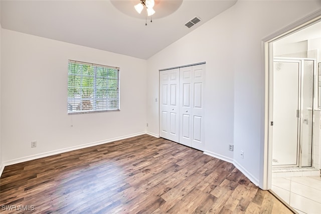 unfurnished bedroom featuring ensuite bath, vaulted ceiling, dark hardwood / wood-style floors, a closet, and ceiling fan