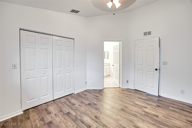 unfurnished bedroom with hardwood / wood-style flooring, ensuite bath, a closet, and ceiling fan