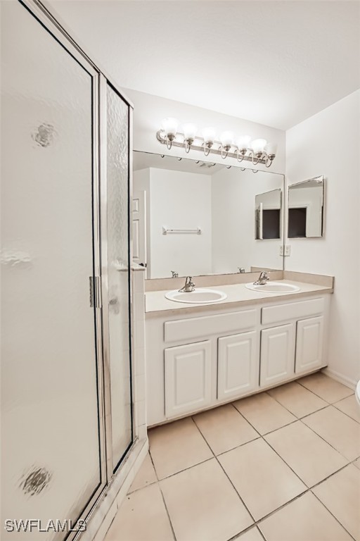 bathroom featuring tile patterned flooring, vanity, and a shower with door