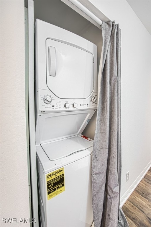 laundry room featuring stacked washing maching and dryer and hardwood / wood-style floors