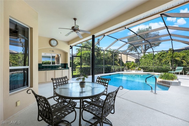 view of swimming pool featuring area for grilling, a lanai, exterior bar, ceiling fan, and a patio