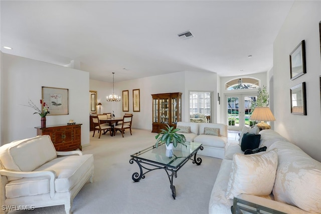 carpeted living room with a notable chandelier and french doors