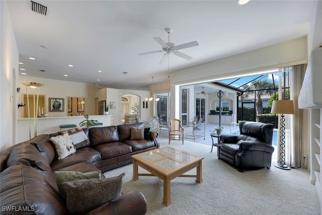 carpeted living room with ceiling fan with notable chandelier