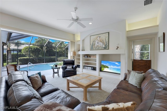 carpeted living room featuring built in shelves and ceiling fan