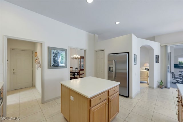 kitchen with a center island, light tile patterned floors, stainless steel refrigerator with ice dispenser, and an inviting chandelier