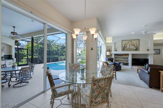 dining space featuring a fireplace, ceiling fan with notable chandelier, light colored carpet, and a wealth of natural light