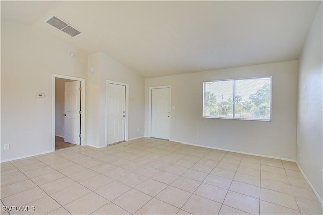 spare room with light tile patterned floors and vaulted ceiling