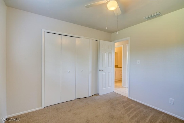 unfurnished bedroom featuring ceiling fan, light colored carpet, and a closet