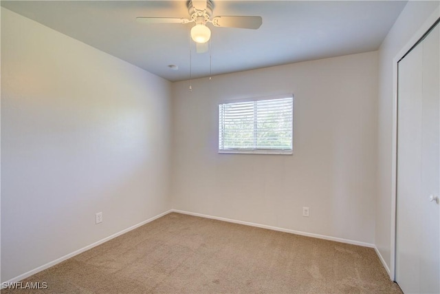 empty room featuring ceiling fan and light colored carpet