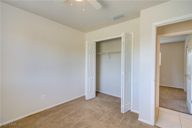 unfurnished bedroom featuring light carpet, a closet, and ceiling fan