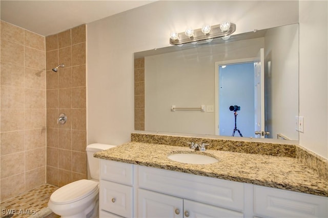 bathroom featuring toilet, vanity, and a tile shower