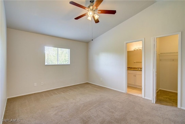 unfurnished bedroom with a spacious closet, light colored carpet, ceiling fan, connected bathroom, and lofted ceiling