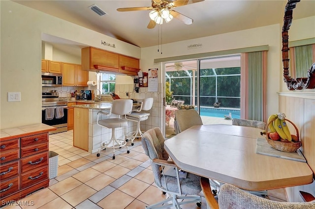 tiled dining room with ceiling fan and sink