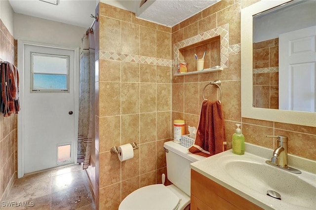 bathroom featuring toilet, vanity, and tile walls