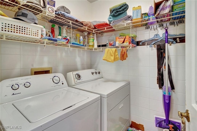 clothes washing area featuring tile walls and washing machine and clothes dryer