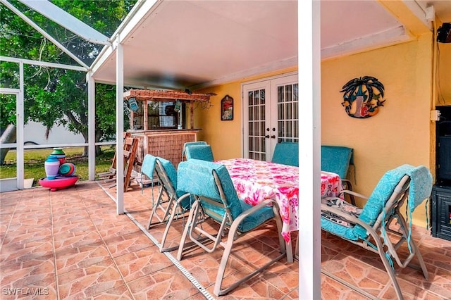 view of patio with glass enclosure, french doors, and exterior bar