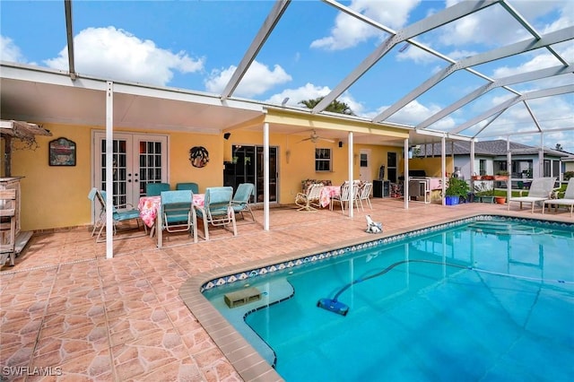 view of pool with ceiling fan, glass enclosure, a patio area, and french doors