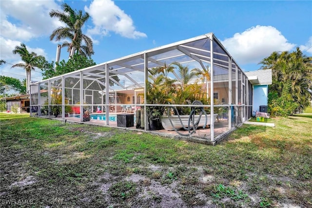 rear view of property with a lawn and glass enclosure