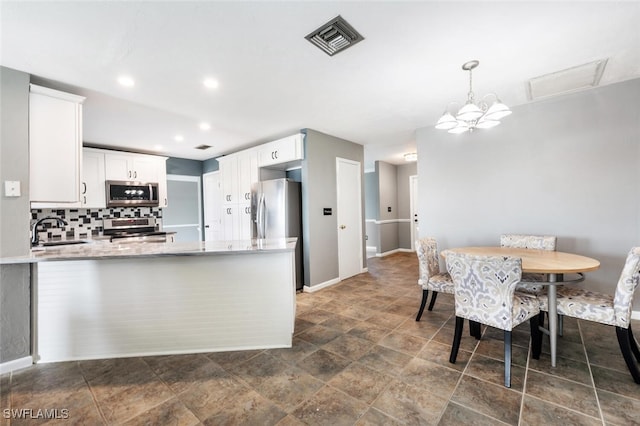 kitchen featuring appliances with stainless steel finishes, decorative light fixtures, sink, and white cabinets